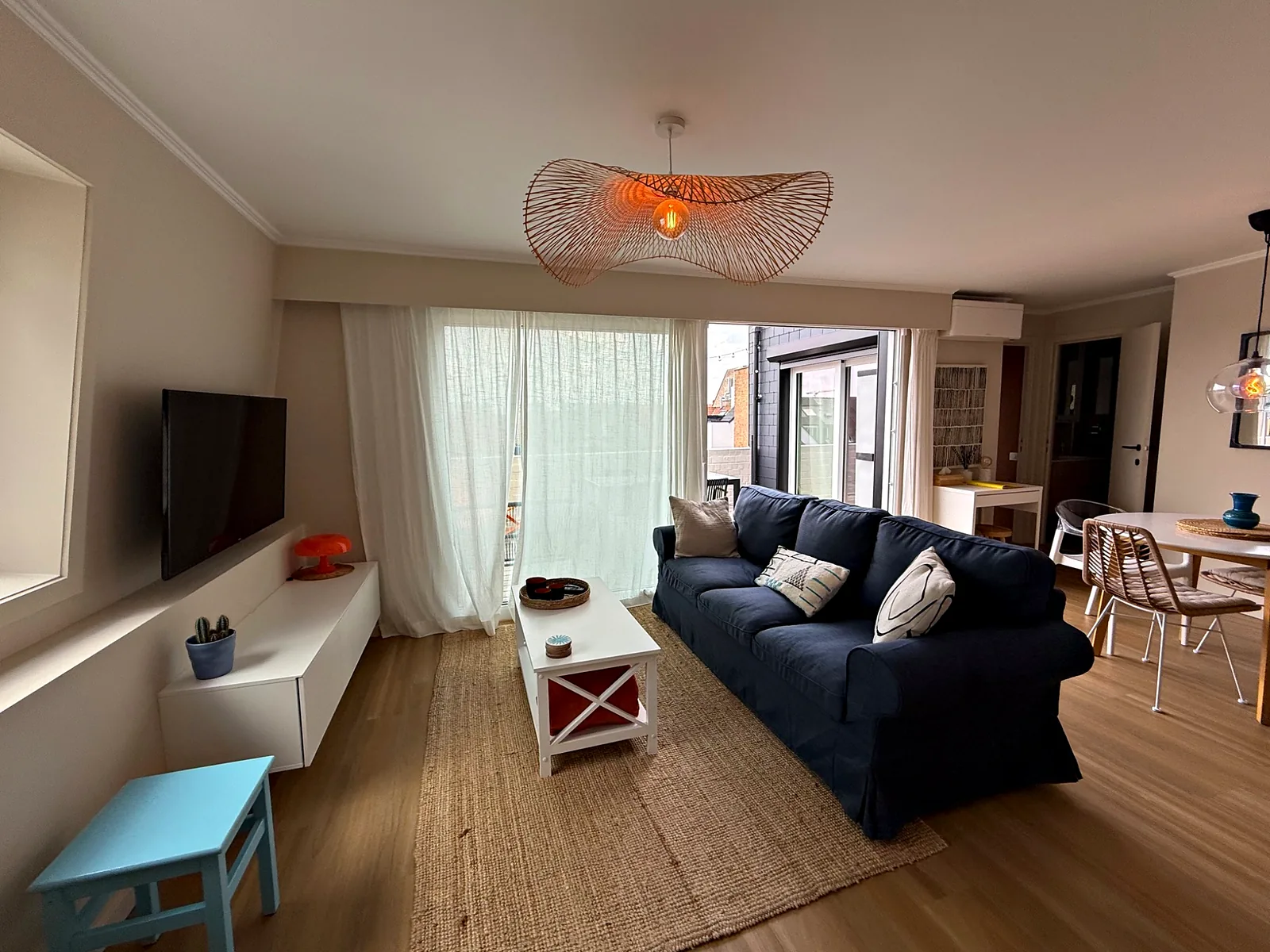 Salon avec canapé bleu, télévision et coin repas