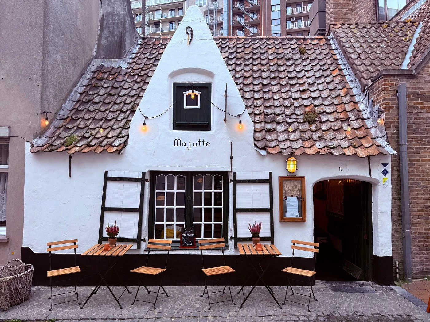 Façade blanchie à la chaux de la maison de pêcheur Majutte, avec tables en terrasse et guirlande lumineuse