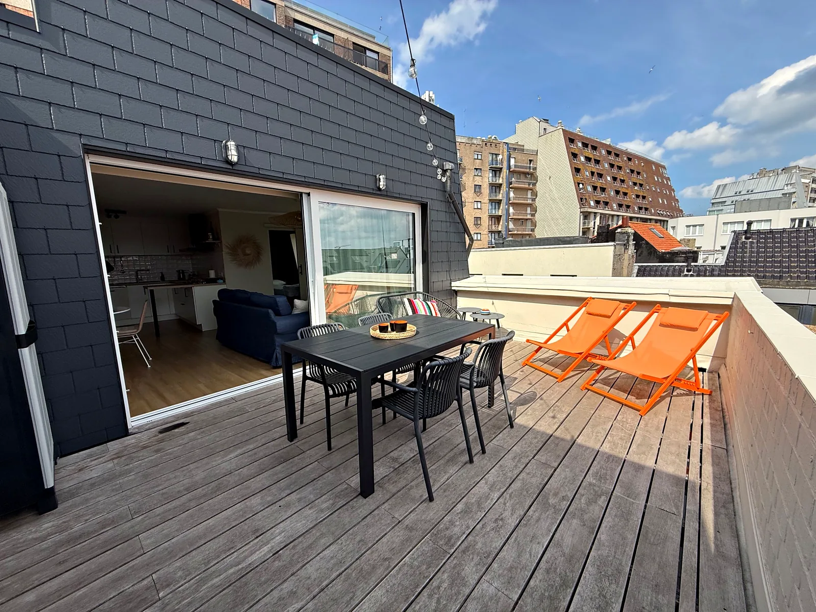 La terrasse en bois vue vers le séjour, avec la table et les transats